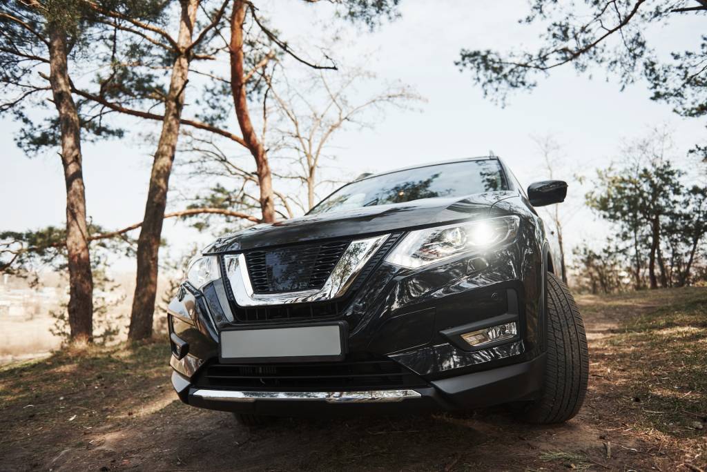 Front view of luxury black modern automobile parked outdoors in the forest.
